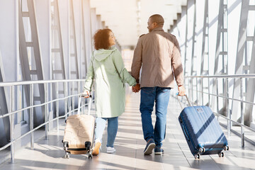 Travelling Together. Romantic African American Couple With Luggage Walking In Airport Terminal,...