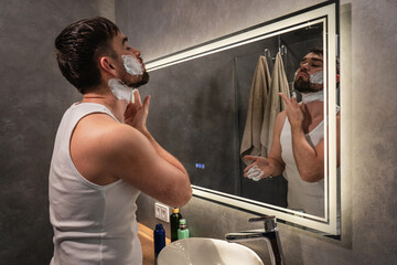Man Applying Shaving Cream in Modern Bathroom Mirror with LED light