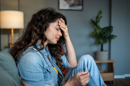 Woman feeling sick holding positive pregnancy test at home