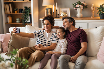 Obraz premium Happy Family Taking a Selfie Together on Sofa at Home