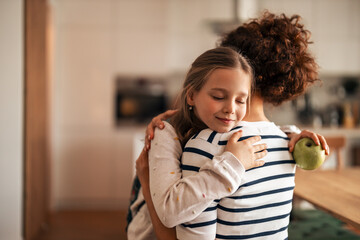 Mother and Daughter Embracing in a Cozy Kitchen Setting