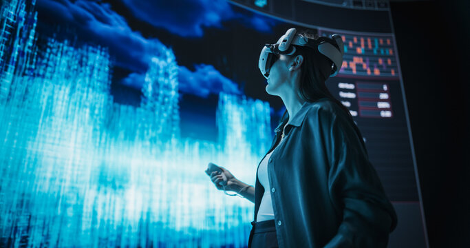 Female Urban Designer Immersed in Virtual Reality, Reimagines a Futuristic City. Virtual Production Screen Displays a Cityscape Polygon Model that is Transformed and Manipulated - Powered by Adobe