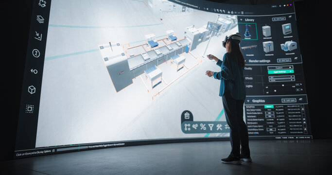 Female Designer in Virtual Reality Headset Expertly Crafts an Automated Factory Layout on a Large Digital Interface. Futuristic Assembly Line Model with Advanced Robotics