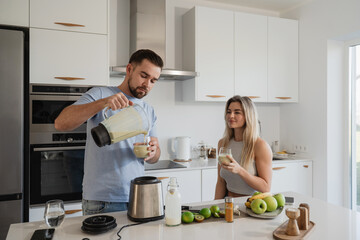 Couple Enjoying Homemade Smoothie Together in Modern Kitchen