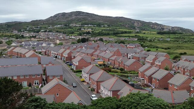 Aerial view circling modern red brick housing neighbourhood under Holyhead mountain in Wales