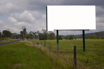 Blank billboard on a rural landscape with cloudy sky, road and fence isolated on white background