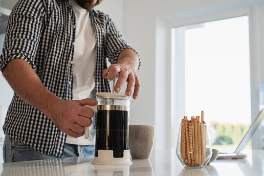 Man preparing  coffee with a French press  in a bright kitchen