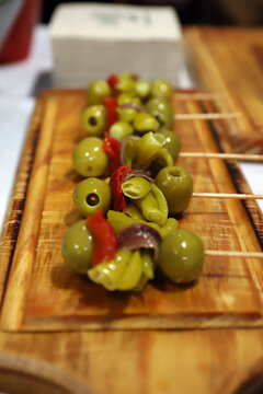 brochetas de gildas con  aceitunas con guindilla, pimiento y anchoas en una tabla de madera