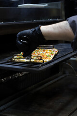 chef sacando una pizza artesanal del horno con sus manos y guantes