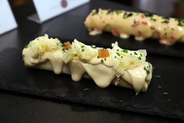 emplatado de canelones rellenos con salsa y queso fundido y especiados