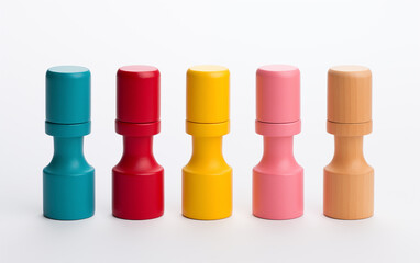 Five colorful wooden toy tops arranged in a row on a white background shot