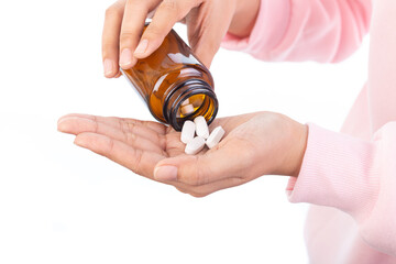 Close-up of hands pouring white tablets from amber medicine bottle. Concept of healthcare,...
