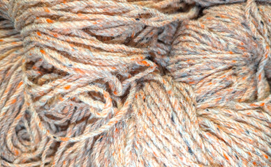 Wool bundles of twisted soft grey and orange yarn are displayed closely together, showcasing their texture and color, in a vibrant marketplace atmosphere. Wool background