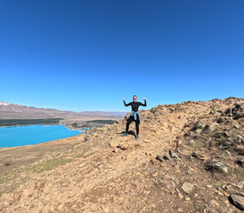 Fototapeta premium Female Hiker Celebrating on Mountain Top near Lake Tekapo, New Zealand