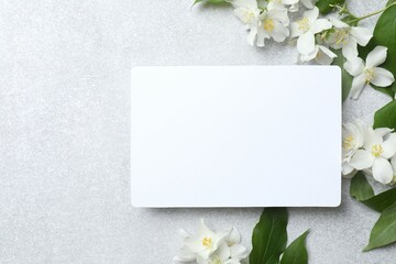 Beautiful white jasmine flowers with paper card on a light background