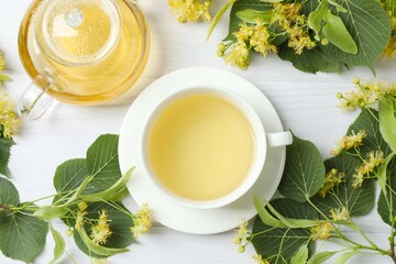 Green tea with fragrant linden in white cup and teapot on wooden background