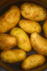 An overhead view of many young potatoes partially submerged in water inside a pot, ready for cooking