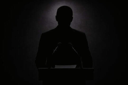 Shadowy Silhouette of Political Figure at Podium with Dramatic Lighting