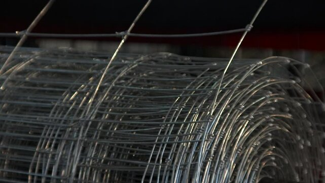A close-up, shallow-depth-of-field view of a large roll of galvanized wire mesh.