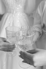 Girls raise a toast with glasses of champagne. Preparation for the wedding. Black and white photo.