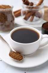 Cup of aromatic coffee and granulated instant coffee on white table, closeup