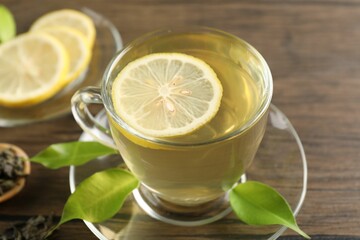 Refreshing green tea with lemon and leaves on wooden table, closeup