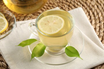 Refreshing green tea with lemon and leaves on table, closeup