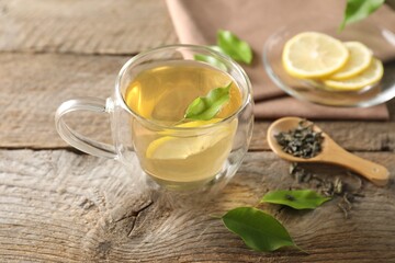 Refreshing green tea with lemon and leaves on wooden table, closeup