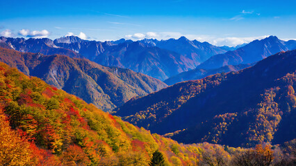 Scenic mountain landscape with autumn foliage, clear blue sky and distant snow-capped peaks.