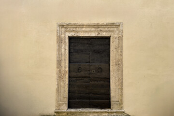 minimalist image of a vintage wooden door with stone frame on light beige wall. historical elegance architectural concept with empty