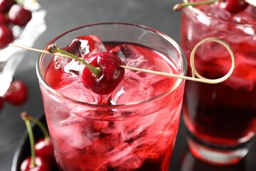 Tasty cherry soda with ice cubes and berries in glasses on grey table, closeup