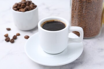 Aromatic hot drink, instant coffee and beans on white marble table, closeup