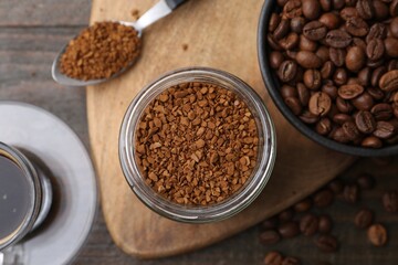 Instant coffee in glass jar, hot drink and beans on wooden table, flat lay