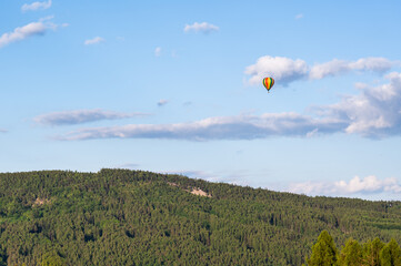 hot air balloon flying in the sky near hill Plešivec in Czech Republic