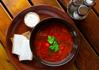 Ukrainian borsch red soup with pork and sour cream , served with bread and salo