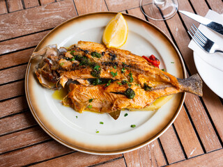 Baked trout divided into two halves served with spices and herbs