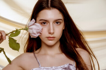 Portrait of brunette with clear skin with pale purple rose near her face