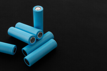 Stack of 18650 cylindrical batteries on black background, rechargeable lithium-ion batteries for electrical appliances and devices. Battery cell or secondary element. With copy space.