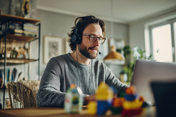 mid-30s man on video call from dining table, wearing headset, working from home