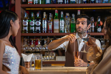 Expatriate bartender skillfully preparing cocktails for two beautiful female customers at a stylish bar counter in Bangkok, Thailand. Warm atmosphere and friendly service in a vibrant city.