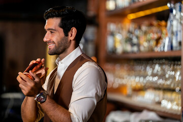 A handsome and focused professional bartender concentrating as he prepares a craft cocktail with a...