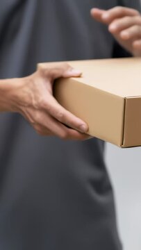 Individual is carefully holding a cardboard package with both hands, highlighting the delivery process and excitement in a simple indoor setting