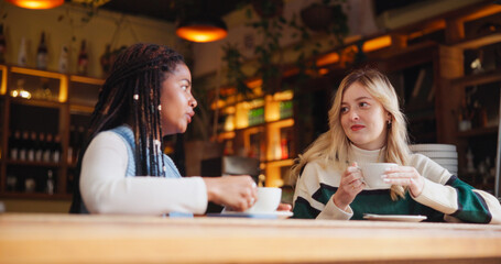 Coffee shop, friends and women with drink in conversation for hangout, reunion and bonding. Restaurant, cafe and people with beverage, talking and gossip for relationship, social chat and relax