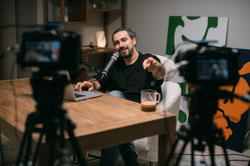Video podcast recording studio. A young man is sitting at a table in front of a microphone in the...