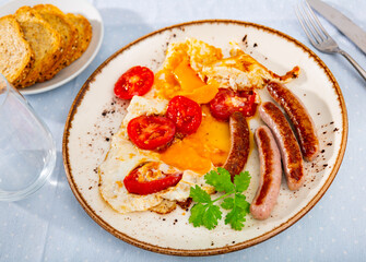Tasty nutritious breakfast of sausage, scrambled eggs and tomatoes