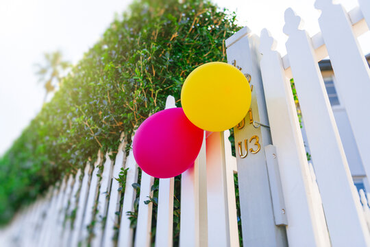 Colourful party ballons on white picket fence