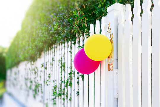 Birthday party balloons at front of white fence