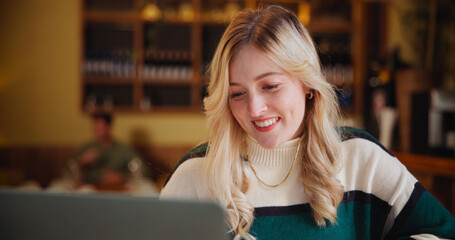 Obraz na płótnie Canvas Happy, student and woman on laptop in coffee shop for learning, online education and assignment in cafe. Restaurant, reading and person on computer for research, school project and university lesson