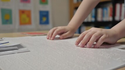 Child reading a Braille book in class.