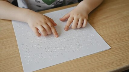 Child reading a Braille book in class.